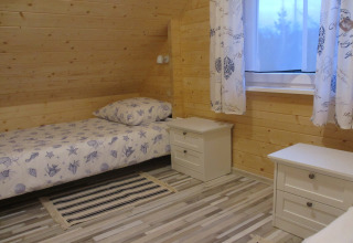 Knusse houten slaapkamer in lodge 'House on a hill' in Duitsland, met eenpersoonsbed en nachtkastjes.