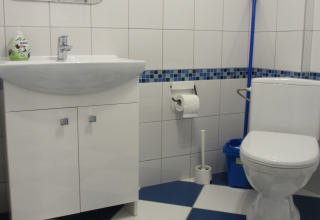 Moderne badkamer met witte wastafel, toilet en blauwe mozaïektegels in House on a Hill, Duitsland.