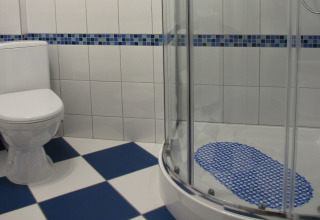 Schone badkamer in 'House on a hill', Duitsland, met toilet, hoekdouche en blauw-wit betegelde vloer.