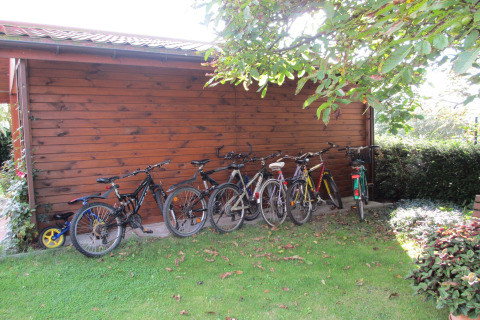 Vijf fietsen staan geparkeerd bij een houten tuinhuis onder een boom bij House on a Hill, Duitsland.