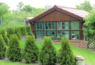 Gezellige houten lodge met groene ramen, omgeven door struiken en tuin bij House on a hill, Duitsland.