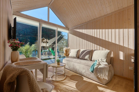 Sala de estar luminosa y acogedora en cabaña de Turkusowa osada Wapnica con grandes ventanales y vista al jardín.