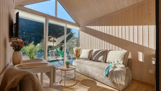 Sala de estar luminosa y acogedora en cabaña de Turkusowa osada Wapnica con grandes ventanales y vista al jardín.