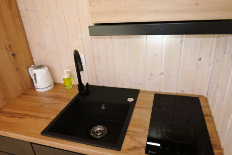Moderne gootsteen, kookplaat en waterkoker op houten aanrecht in de Turkusowa osada Wapnica cabin.