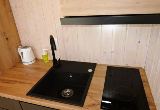 Moderne gootsteen, kookplaat en waterkoker op houten aanrecht in de Turkusowa osada Wapnica cabin.