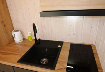 Moderne Spüle, Kochfeld und Wasserkocher auf Holzarbeitsplatte in der Hütte Turkusowa osada Wapnica.