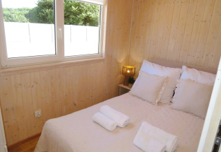 Dormitorio luminoso en cabaña de madera con cama doble y vistas a la naturaleza en Turkusowa osada Wapnica.