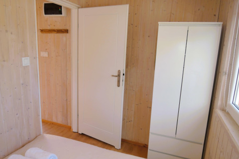 Lichte houten kamer met witte deur, witte kast en raam in Turkusowa osada Wapnica hut.