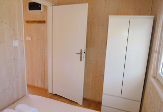 Lichte houten kamer met witte deur, witte kast en raam in Turkusowa osada Wapnica hut.