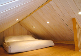 Knusse mezzanine met laag houten plafond en tweepersoonsbed in een hut bij Turkusowa osada Wapnica, Duitsland.