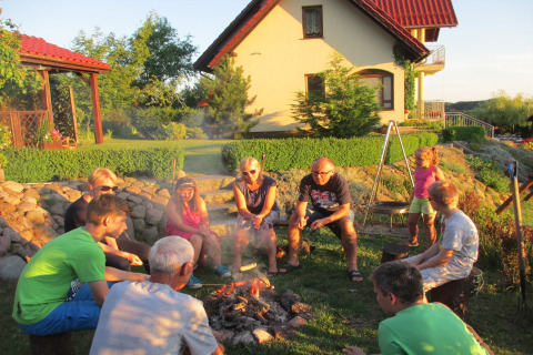Familie en vrienden rond een kampvuur bij het Huis op de Heuvel in Duitsland op een zomerse avond.