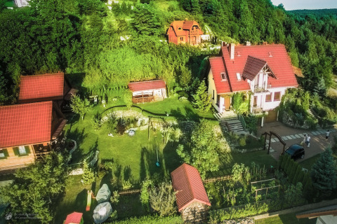 Luchtfoto van pension 'House on a hill' in Duitsland, met rode daken, groene tuin en omliggend bosgebied.