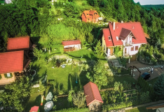 Luchtfoto van pension 'House on a hill' in Duitsland, met rode daken, groene tuin en omliggend bosgebied.