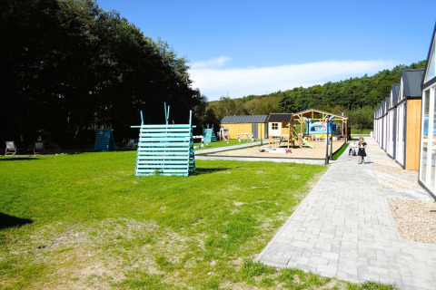 Parque infantil con césped, arenero y casita de juegos en Turkusowa Osada Wapnica, día soleado en Alemania.