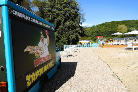 Foodtruck met zapiekanki-reclame naast een grindpad bij strandbedden in Turkusowa osada Wapnica, Polen.