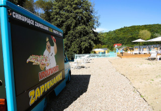 Foodtruck met zapiekanki-reclame naast een grindpad bij strandbedden in Turkusowa osada Wapnica, Polen.