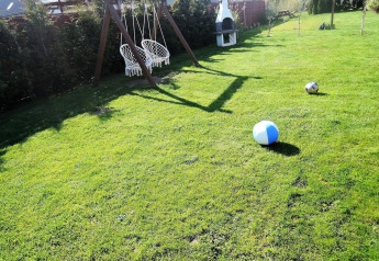 Pelouse avec balançoires, barbecue et ballons à la cabane 'Peace and quiet - cottage for 4 people' en Allemagne.