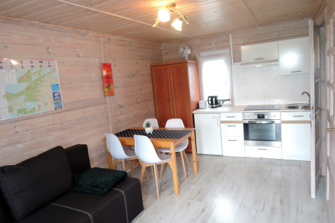 Interior de cabaña acogedora en Alemania, con cocina moderna, mesa de comedor y sofá para 4 personas.