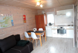 Gemütliches Wohnzimmer einer Hütte mit moderner Küche, Essbereich und Sofa für vier Personen in Deutschland.