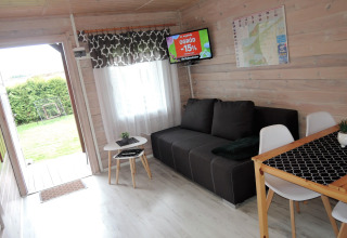 Gemütliches Ferienhaus für 4 Personen mit Wohnzimmer, Sofa, Essbereich und Blick in den Garten in Deutschland.