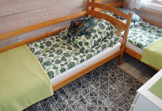 Two single beds in a cabin with tropical leaf-patterned bedding and green throws, located in Germany.