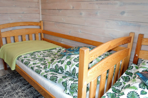 Two single beds with leaf-pattern bedding in a cozy wooden cabin for four people in Germany.