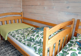 Dos camas individuales con ropa de cama de hojas en una acogedora cabaña de madera para cuatro personas en Alemania.