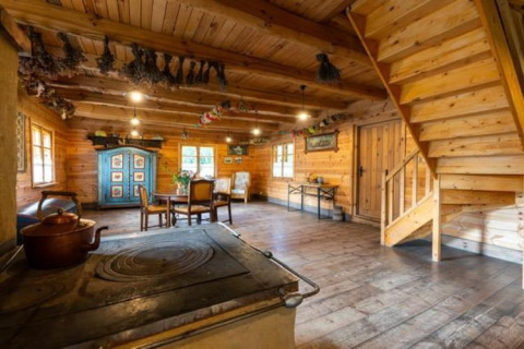 Interno di lodge rustico con pareti in legno, stufa a legna, tavolo da pranzo e scala in legno.
