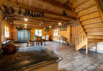 Interno di lodge rustico con pareti in legno, stufa a legna, tavolo da pranzo e scala in legno.