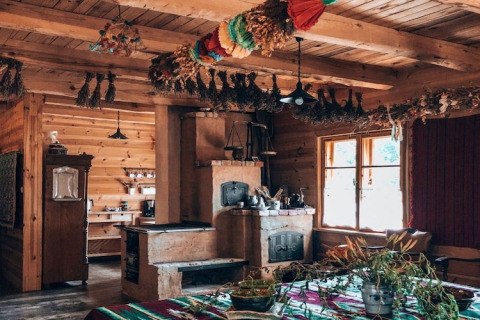 Knusse houten lodge met gedroogde kruiden die aan het plafond hangen en zonlicht door het raam schijnt.