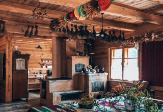 Knusse houten lodge met gedroogde kruiden die aan het plafond hangen en zonlicht door het raam schijnt.
