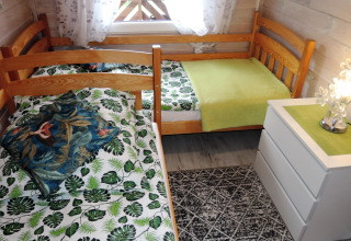 Gemütliches Schlafzimmer mit zwei Einzelbetten, grüner Bettwäsche und Kommode in einer Holzhütte.