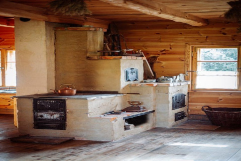 Traditionele houtkachel in een knusse houten lodge, zonlicht valt zacht naar binnen door het venster.