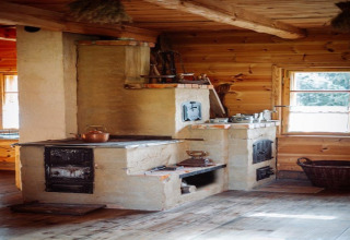 Traditioneller Holzofen in einer rustikalen Hütte, Sonnenlicht fällt durch das Fenster auf den Ofen.