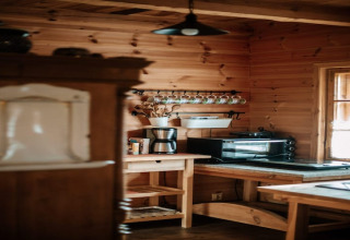 Gezellige houten keuken met koffiemachine, oven en mokkenrek in een lodge in Bełczna, Duitsland.