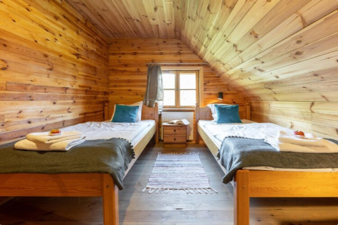 Houten slaapkamer met twee enkele bedden en raam, House by the road Skansen, Bełczna, Duitsland.
