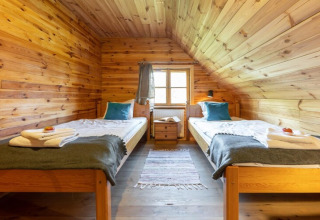 Wood-paneled twin room with beds, pillows, and a window at House by the road Skansen, Bełczna, Germany.