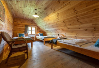 Met hout beklede kamer met drie bedden in House by the road Skansen voor 8 personen, Bełczna, Duitsland.