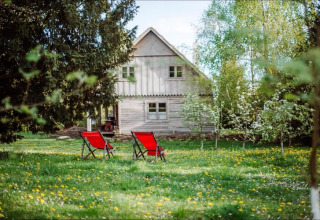 Due sedie rosse sul prato davanti a una casa in legno a Skansen, Bełczna, Germania.