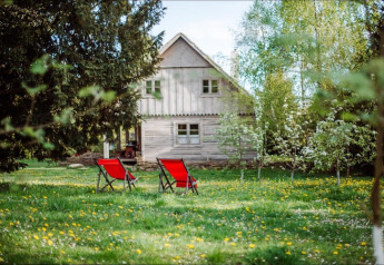 Due sedie rosse sul prato davanti a una casa in legno a Skansen, Bełczna, Germania.