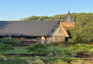 Gemütliches Holzhaus in Bełczna, Deutschland, mit Garten und Kirchturm im Hintergrund im Sommer.