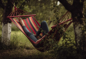A person relaxing in a colorful hammock tied between two trees at House by the road Skansen in Bełczna.