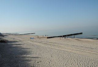 Peaceful beach with soft sand, wooden breakwaters, and calm sea, seen from a cottage in Germany.