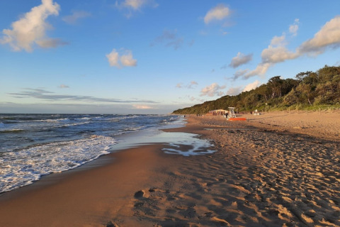Rustig uitzicht op een leeg zandstrand met golven en blauwe lucht bij een huisje voor 4 personen in Duitsland.