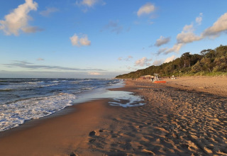 Rustig uitzicht op een leeg zandstrand met golven en blauwe lucht bij een huisje voor 4 personen in Duitsland.