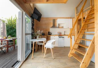 Maison de plage moderne près du lac Klępnica en Allemagne, cuisine bois, coin repas et escalier mezzanine.