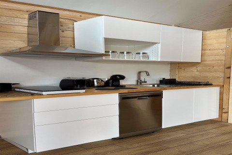 Modern kitchen in 'House by Lake Klępnica' beach house in Germany, white cabinets, wood and steel appliances.