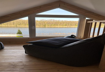 Mezzanine avec grande fenêtre donnant sur le lac Klępnica en Allemagne, fauteuil poire confortable.