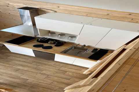 Cocina moderna de casa de playa en madera y blanco, con estufa, fregadero y estantes en Lake Klępnica, Alemania.