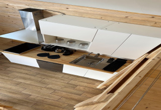 Moderne strandhuiskeuken in hout en wit, met fornuis, gootsteen en planken bij Lake Klępnica in Duitsland.